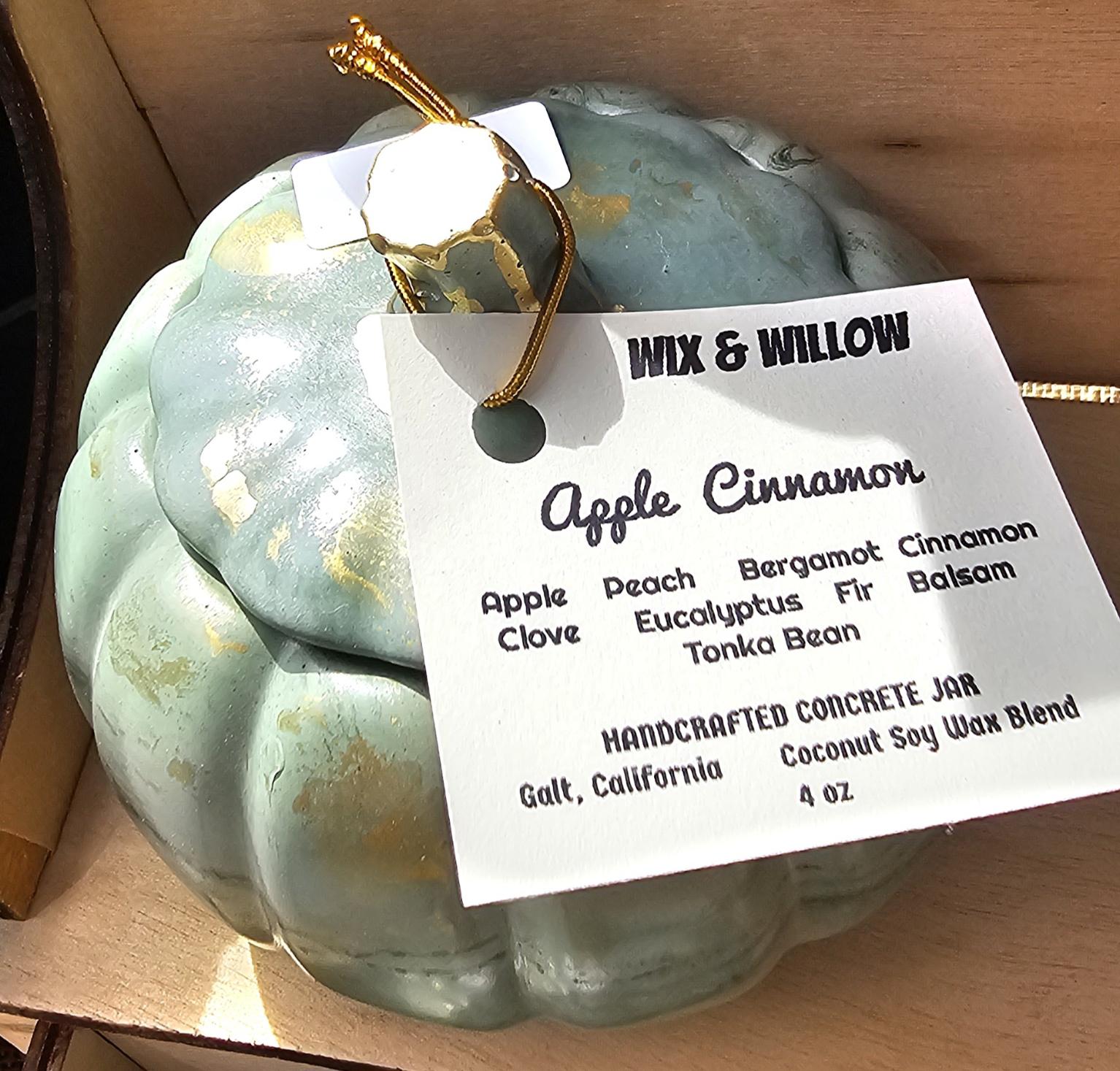 Sage green pumpkin-shaped concrete candle tagged Apple Cinnamon